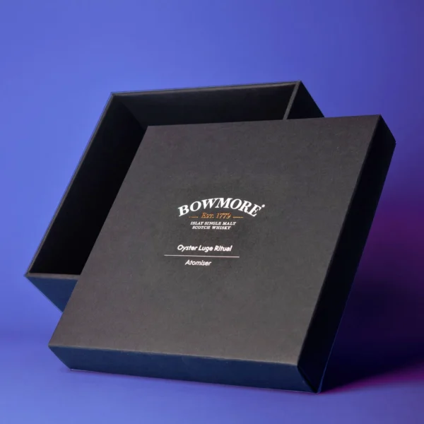 The image showcases a black box for the Bowmore Oyster Luge Ritual Atomizer. The box has a simple design and is made of a textured black cardboard.